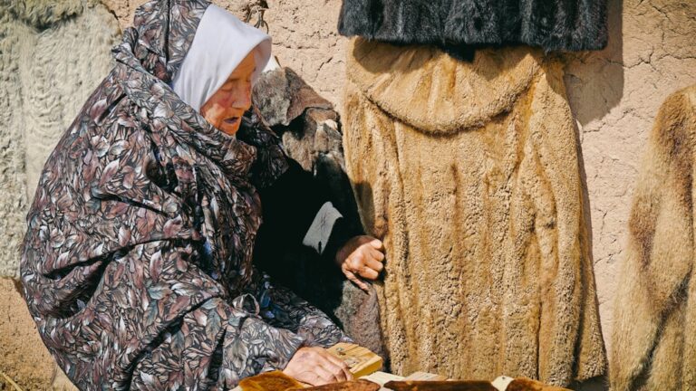 Woman examines coats at a market stall.