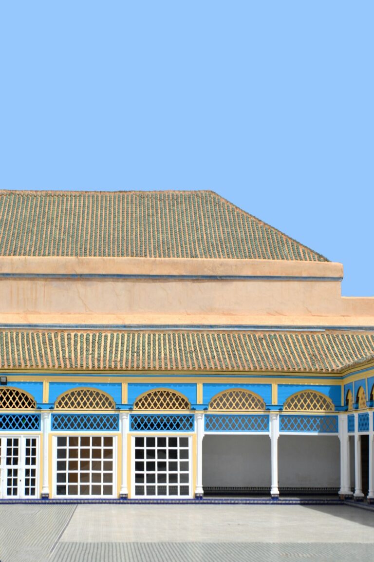A section of the iconic Bahia Palace in Marrakech, Morocco. The vivid blue and yellow details, traditional arches, and...