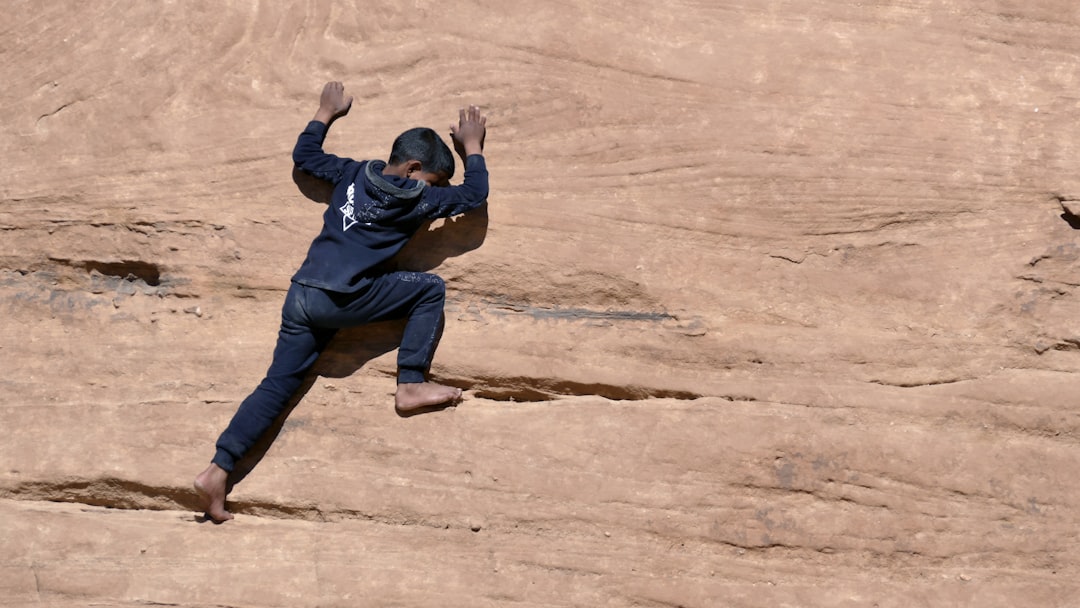 man in blue jacket and blue denim jeans lying on brown sand during daytime