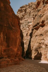 a man walking through a narrow canyon in the desert