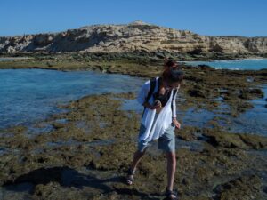 A person explores a rocky seashore.